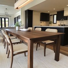 a large wooden table sitting in the middle of a living room next to a kitchen