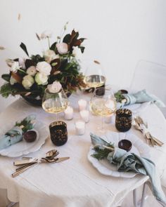 the table is set with plates, silverware and flowers in vases on it