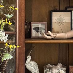 a wooden shelf with flowers and pictures on it