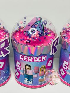 three tins filled with pink and purple sprinkles on top of each other