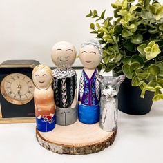 three wooden figurines sitting on top of a table next to a clock and potted plant