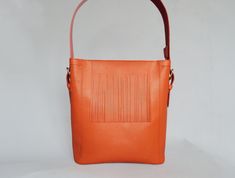 "Original bright leather shoulder hobo bag made of quality natural leather in orange and red color color. Comfortable and durable, it is designed it to be your perfect everyday bag, The red fringe is detachable and the strap has two sides - red and orange. You can wear it two colored and orange only depending on your outfit. The bag features zipper closure, one big inside compartment and leather slip pocket. You won't be unnoticed with this bag! Size: height - 13\"/ 34 cm width - 13\"/ 34 cm dep Orange Crossbody Bucket Bag, Modern Orange Crossbody Shoulder Bag, Modern Orange Shoulder Bag With Adjustable Strap, Orange Bucket Bag With Removable Pouch For Shopping, Modern Orange Leather Shoulder Bag, Orange Bucket Bag For Everyday Use, Orange Bucket Bag With Leather Handles, Orange Satchel Bucket Bag For Daily Use, Orange Rectangular Bucket Bag For Shopping