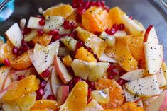 fruit salad with oranges, apples and pomegranates in a glass bowl