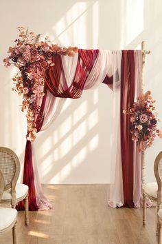 a wedding arch decorated with flowers and sheer draping for the bride's ceremony