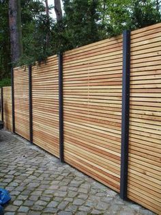 a wooden fence is lined with black metal posts and wood slats on the sides