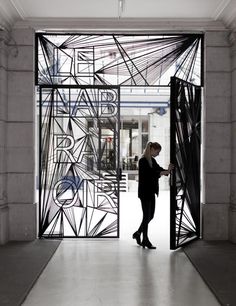 a woman standing in front of an open door with abstract designs on the glass panels