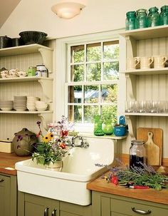 a white sink sitting under a window next to a counter top with dishes on it