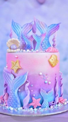 a pink and blue cake with mermaid decorations