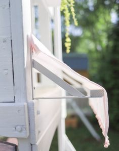 a close up of the side of a white house with flowers hanging from it's roof