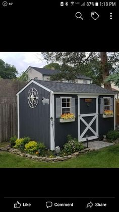 a small gray and white shed with flowers in the window boxes on the side of it