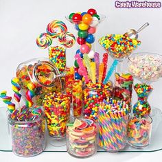 a table topped with lots of candy and lollipops on top of glass containers