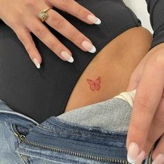 a woman's stomach with a butterfly tattoo on her left side, and two fingers in the other hand