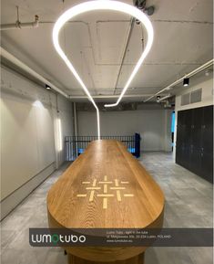 a long wooden table with an illuminated cross on it's top in a large room