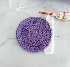 a crocheted doily with a crochet hook in the middle on a marble surface