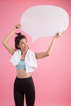 a woman holding a white speech bubble above her head and wearing black leggings