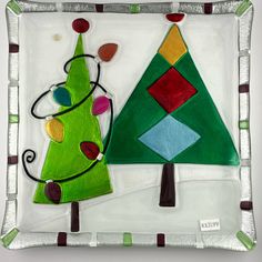 a decorative glass plate with a christmas tree and a small green ornament on it