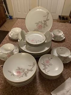 a table topped with lots of white plates and cups on top of a granite counter