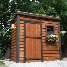 a small wooden shed with flowers in the window