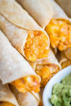 several tortillas with guacamole and salsa in a bowl on the side