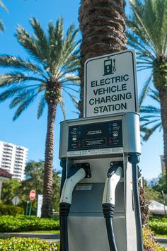 an electric vehicle charging station with palm trees in the background