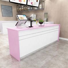 a pink and white counter in a store with two monitors on the wall above it