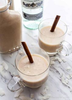 two glasses filled with liquid and cinnamon sticks