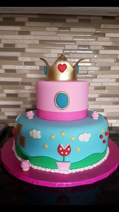 a three tiered cake with a princess crown on top, sitting on a table