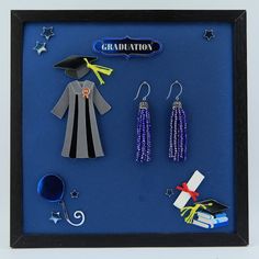 a shadow frame with graduation decorations and items in it, including a graduate's cap