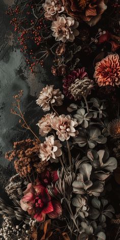 a bunch of flowers that are on top of a table with leaves and berries around them