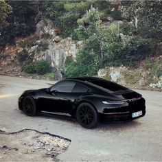 a black sports car is parked on the side of the road in front of some rocks