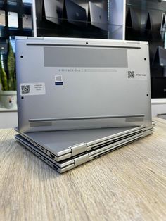 an open laptop computer sitting on top of a wooden table in front of some shelves