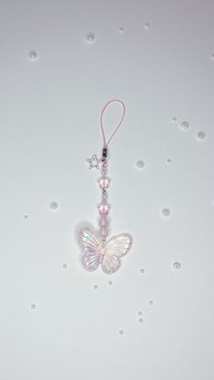 a white butterfly is hanging from a pink string on a white surface with bubbles around it