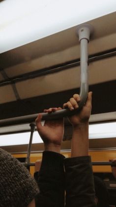 two people are sitting on a bus and one is holding up the handle to their head