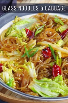 a bowl filled with noodles and vegetables on top of a wooden table