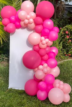 a bunch of balloons are on the ground near a white board with pink and pink colors