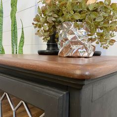 a potted plant sitting on top of a wooden table next to a metal container