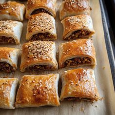 many different types of pastries on a baking sheet with sesame seeds and seasoning