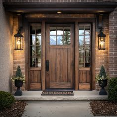 the front door of a house with two planters on either side and one light on