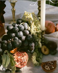 a table topped with lots of fruit and veggies next to a lit candle