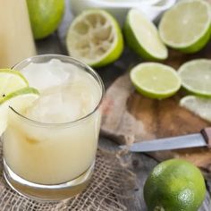 a glass filled with lemonade next to limes