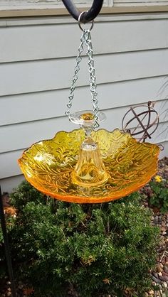 a yellow glass bowl hanging from a chain on a house's front lawn area