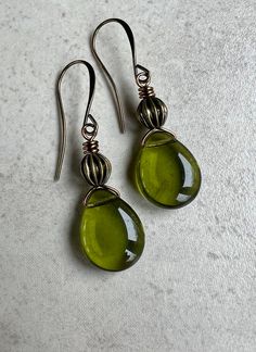 "olive green earrings   boho dangle earrings    czech glass teardrop earrings * Czech glass flat teardrop beads - 12x16mm * transparent shiny olive green color * corrugated antiqued brass bead sits on top * you choose - leverback or hook ear wires - both antiqued     brass * total length - with leverbacks, 1 5/8\" - with hook ear wires,     1 3/4\" * you can enter my shop here:    gypsydangles.etsy.com" Cute 70s Earrings, Green Czech Glass Teardrop Jewelry, Green Teardrop Czech Glass Jewelry, Green Teardrop Glass Jewelry, Green Teardrop Metal Earrings, Handmade Green Teardrop Earrings, Green Teardrop Drop Earrings Nickel Free, Green Nickel-free Teardrop Drop Earrings, Green Nickel-free Teardrop Earrings