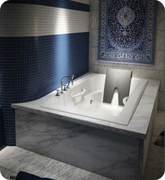 a white bath tub sitting under a blue and white tile wall next to a sink