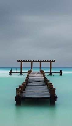 a long wooden dock sitting in the middle of blue water