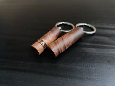 two wooden cylinders with metal handles on a black surface, one is open and the other is closed