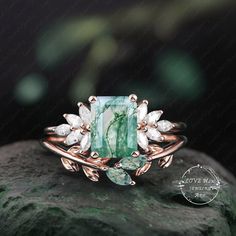 a green and white ring sitting on top of a rock next to a leafy plant