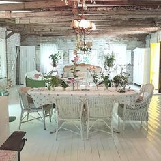 the dining room is decorated with white wicker furniture and flowers in vases on the table