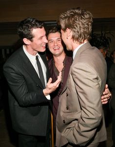 three men in suits are laughing together at an event