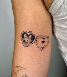 a woman's arm with two small tattoos on it, one has a cat and the other has a heart