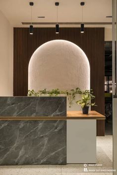 an office lobby with a marble counter and plant in the center, surrounded by wood paneling